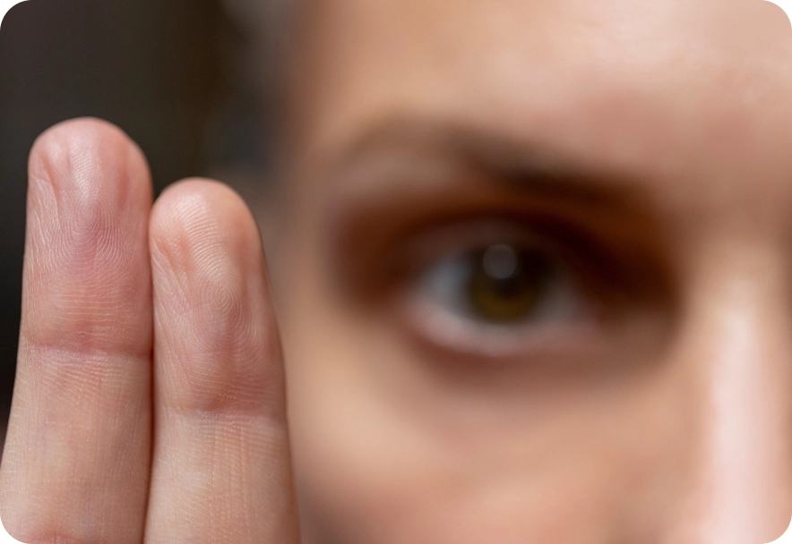 Close-up image of a person looking into the camera and holding up two fingers.